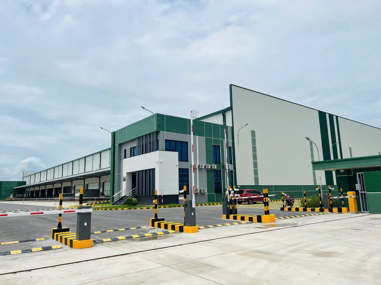 Nhà xưởng công nghiệp hiện đại với cổng bảo vệ và khu vực bãi xe phía trước